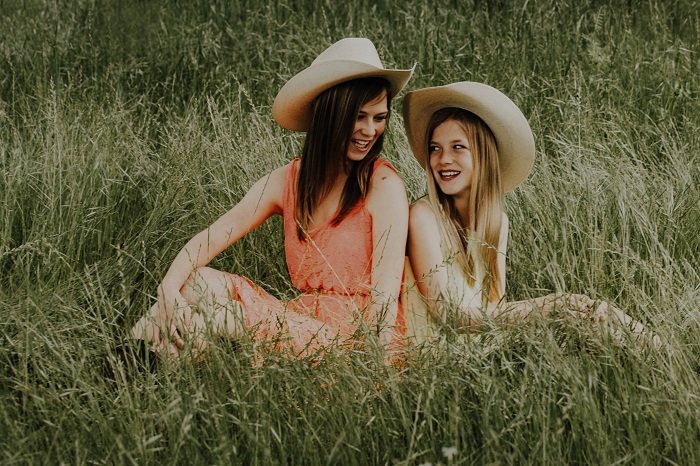 Две девушки в ковбойских шляпах сидят в поле идея фотосессии сестер