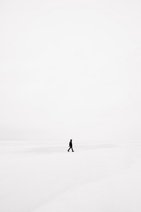 Пример сюрреалистической фотографии, где человек идет по чистому белому пейзажу