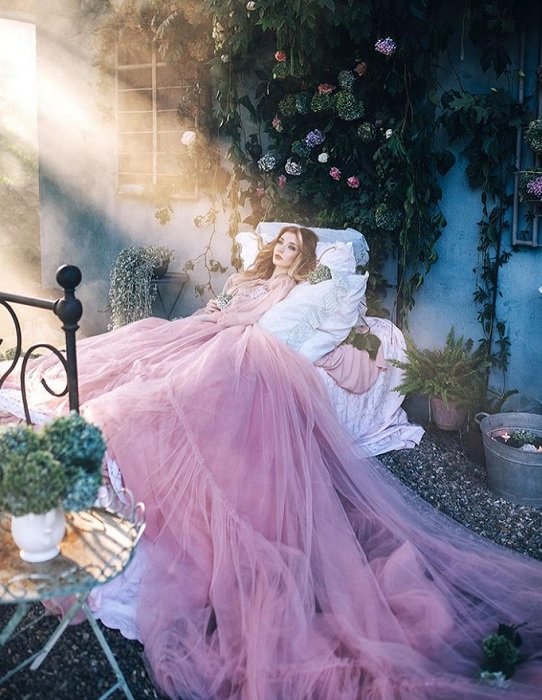 Женщина в розовом платье на кровати в саду как пример сказочной фотографии