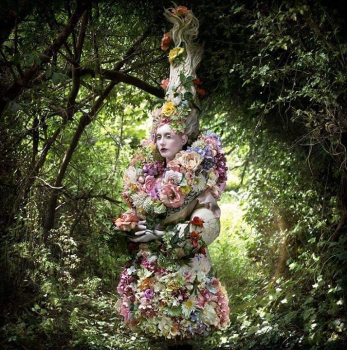 Женщина в сложном цветочном наряде из сказки в лесу