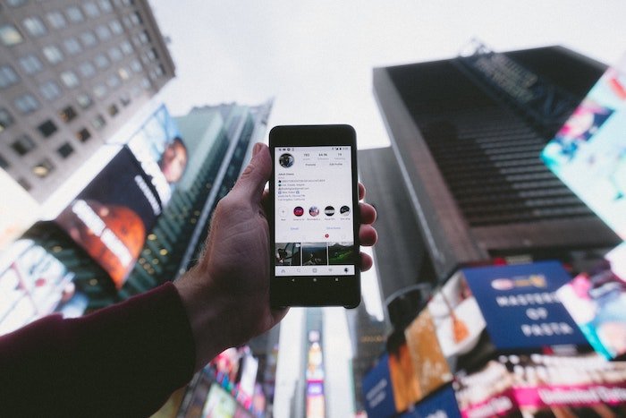 Человек держит телефон в воздухе, показывая биографию на Instagram
