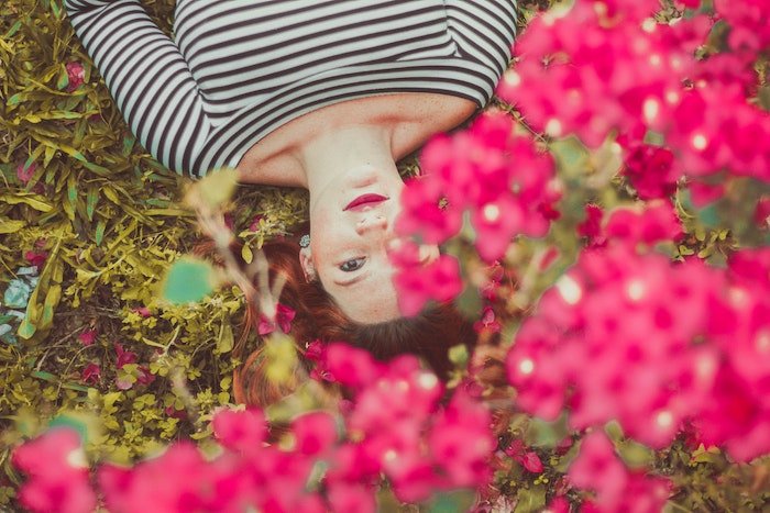 Портрет лежащей на земле женщины с цветами на переднем плане