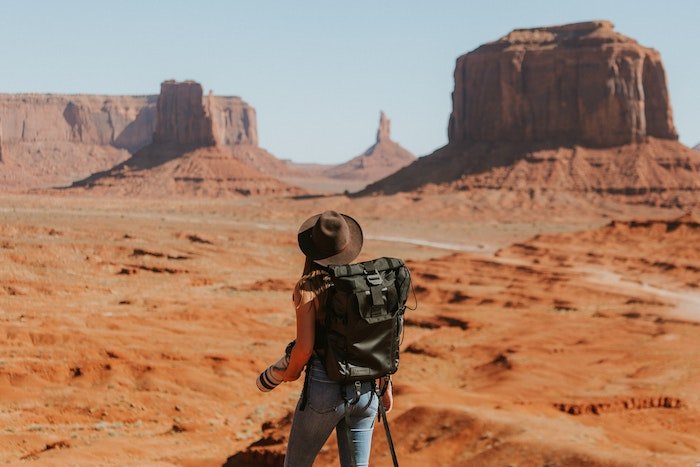 Путешествующий фотограф идет с камерой в руках по пустыне