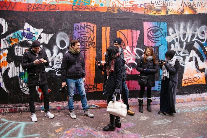 Группа фотографов в фотомастерской стоит перед стеной граффити