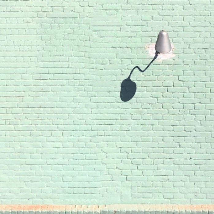 Мятно-зеленая кирпичная стена с лампой как пример композиции эстетической фотографии