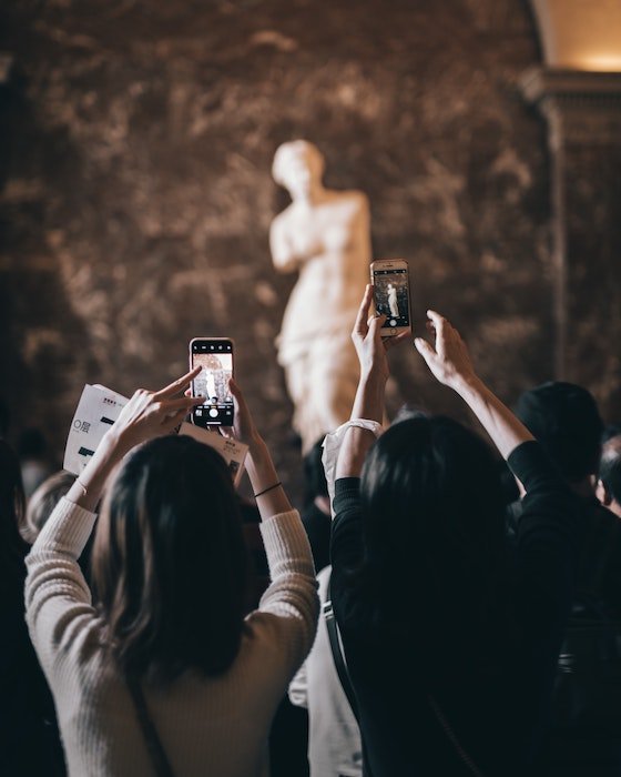 Люди фотографируют скульптуру на заднем плане смартфонами