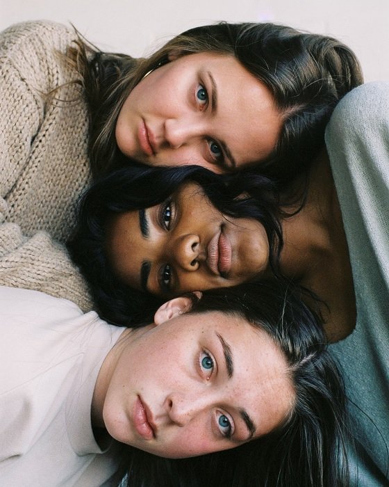 Три молодые женщины со сложенными вместе головами для фотосессии лучшей подруги