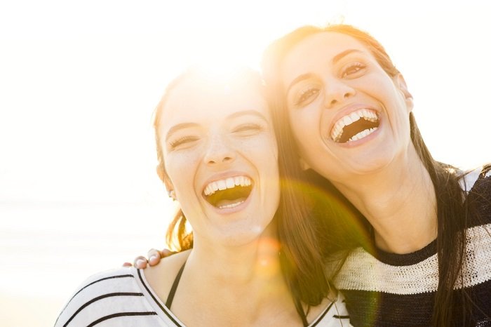 Две женщины смеются с солнечными бликами