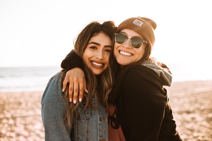 Две подруги стоят рядом на пляже как идея для фотосессии лучших друзей