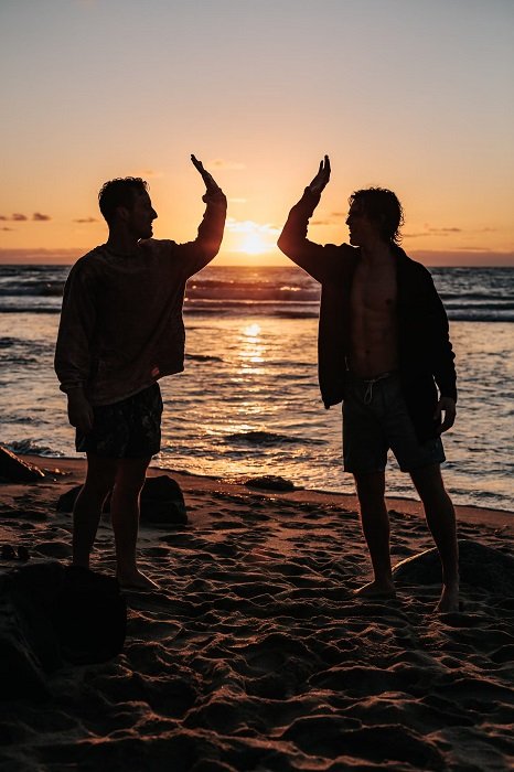 Двое мужчин дают пять на пляже