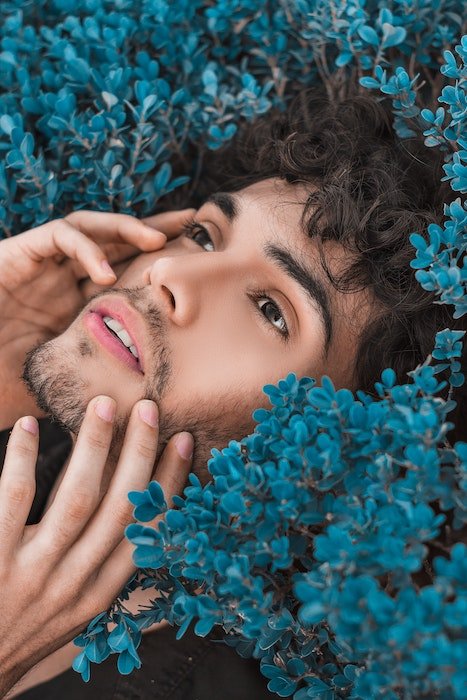 Мужчина держит лицо в окружении цветов