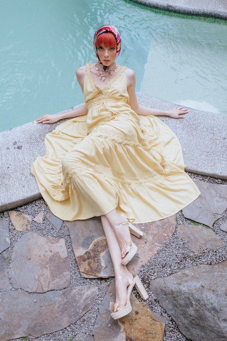 Женщина, лежащая у бассейна в желтом платье и платке, как пример позы модели