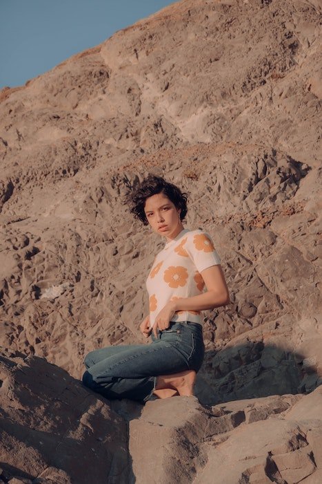 Женщина стоит на коленях на камнях на открытом воздухе как идея для модельных поз