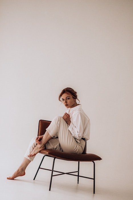 Женщина, сидящая в кресле с поднятой ногой, как идея для модельных поз