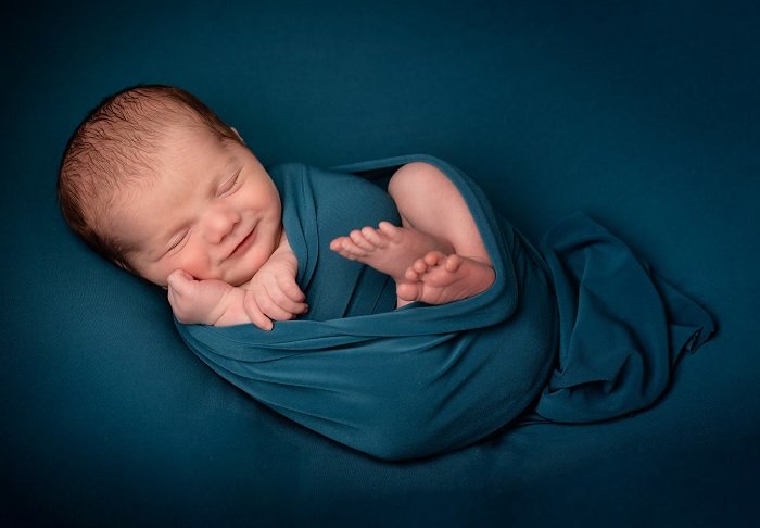 Ребенок завернут в голубое одеяло для фотосессии новорожденных