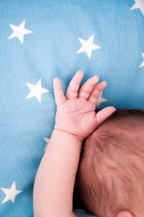 Рука и рука младенца на голубом одеяле как идея для фотографий новорожденных