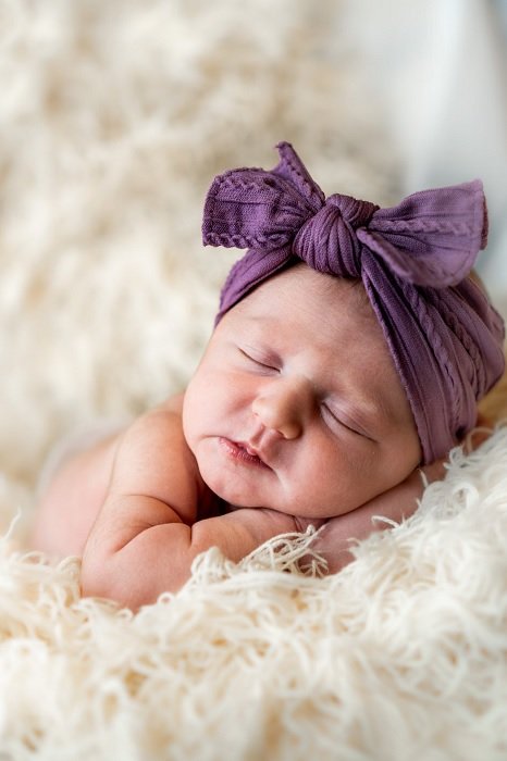 Малыш с бантом на голове как идея для фотосессии новорожденных