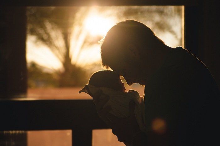 Отец держит ребенка за голову как идея фото новорожденного