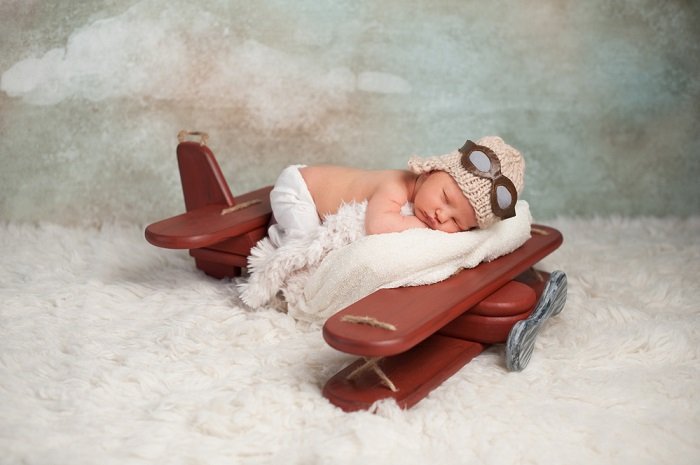 Младенец, спящий в сцене на авиационную тему, как пример идей для фото новорожденных