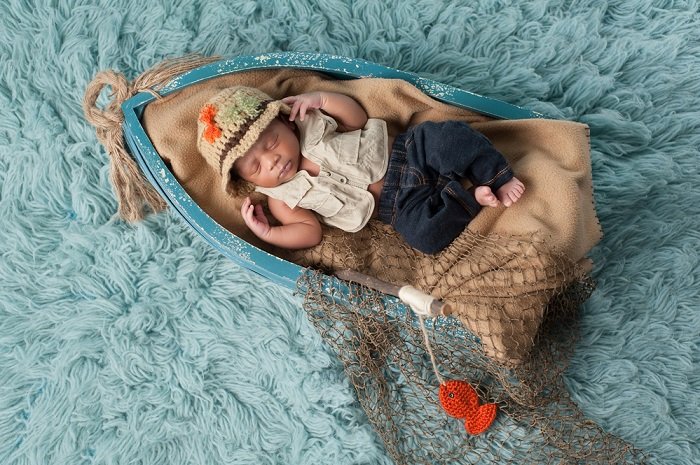 Ребенок спит в миниатюрной лодке для фотосессии новорожденных