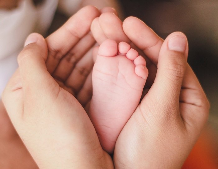 Взрослые руки, обхватывающие ногу ребенка как идея для фото новорожденных