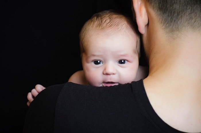 Ребенок смотрит через плечо отца как идея для фотографий новорожденных