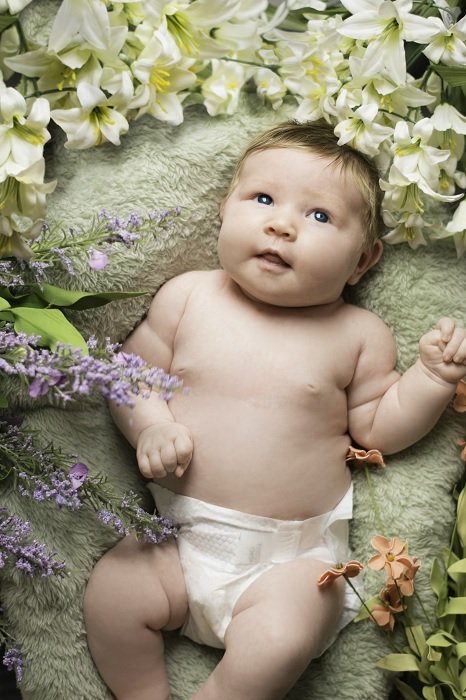 Малыш в окружении цветов как пример фотосессии новорожденного