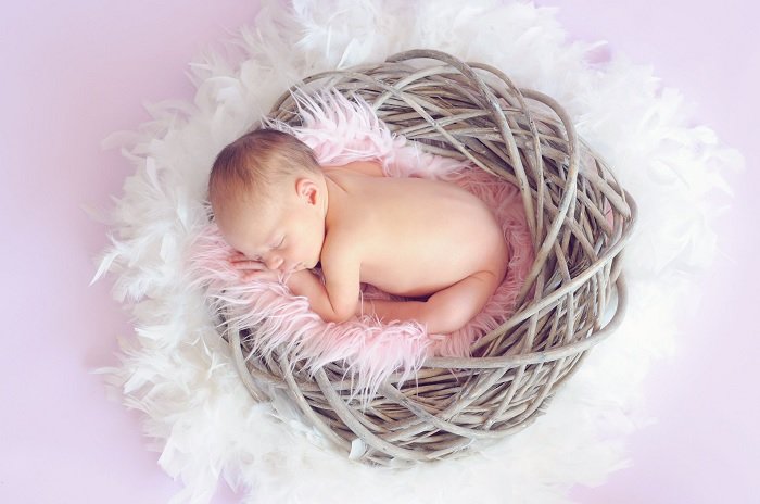Малыш спит в гнездышке для фотосессии новорожденных