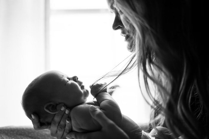 Черно-белая фотография матери, держащей младенца перед собой, пример фотографии новорожденного