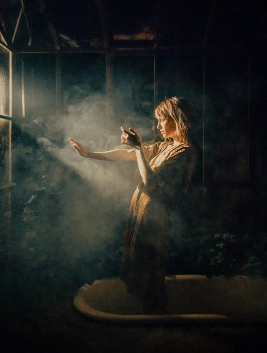 Женщина стоит в дымчатом свете окна