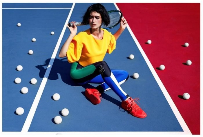Женщина в красочной одежде сидит на теннисном корте