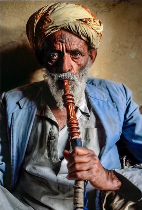портрет мужчины из йемена, курящего трубку кальяна