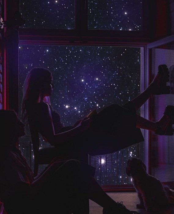 Два человека и кошка сидят перед звездным окном