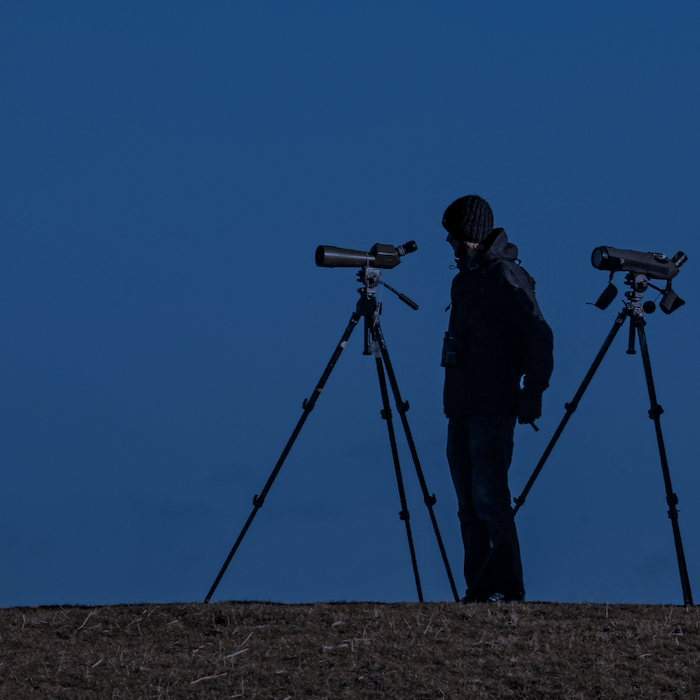 Человек стоит с двумя телескопами для астрофотографии