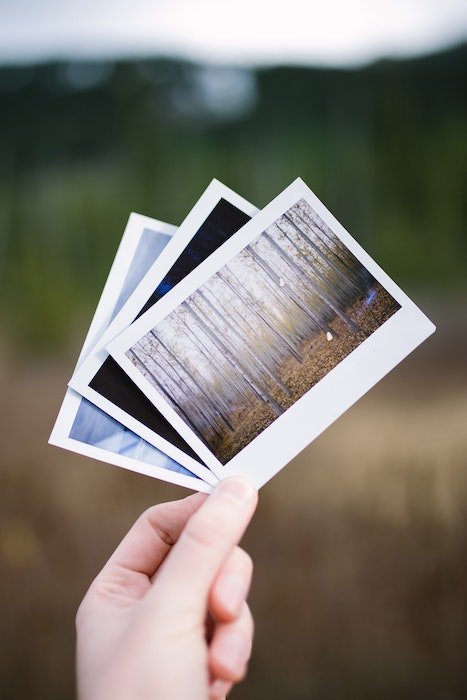 Рука держит три напечатанные глянцевые фотографии