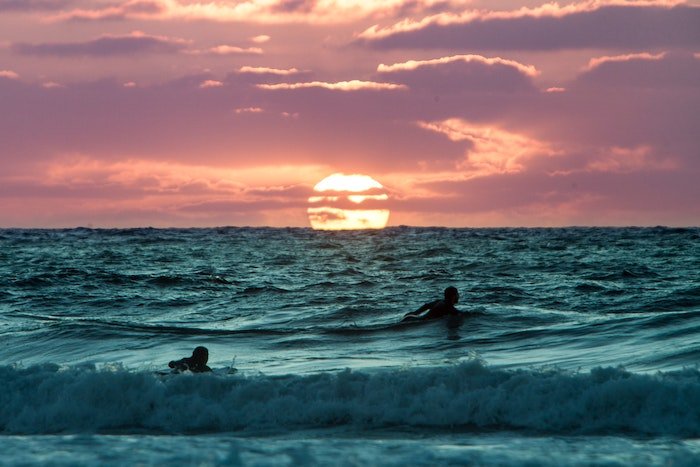 Серферы в воде на закате как идея для серф-фотографии