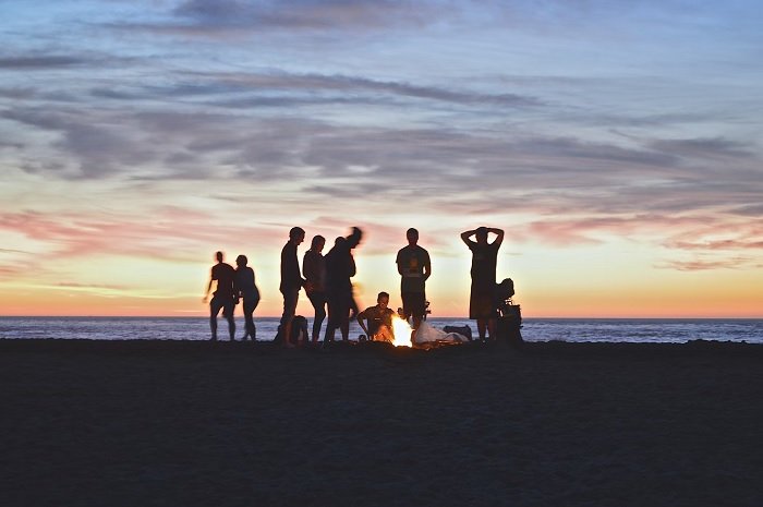 Группа друзей на пляже на закате