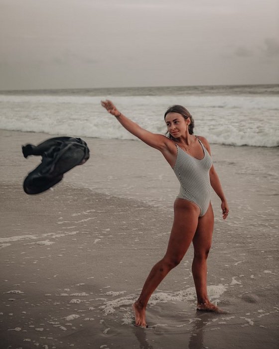Женщина в купальнике бросает полотенце на пляже идея позы бикини