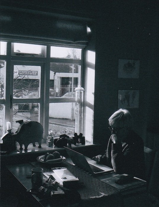 Женщина за компьютером сидит у окна, снятого в черно-белом цвете