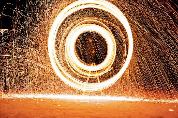 Long exposure photo of the man creating circles with the sparkler