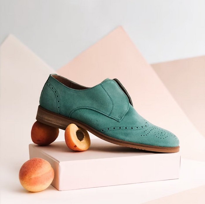 Фотография продукта зеленой туфли с персиком под ней