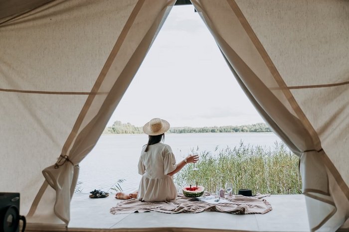 Женщина сидит у палатки рядом с озером