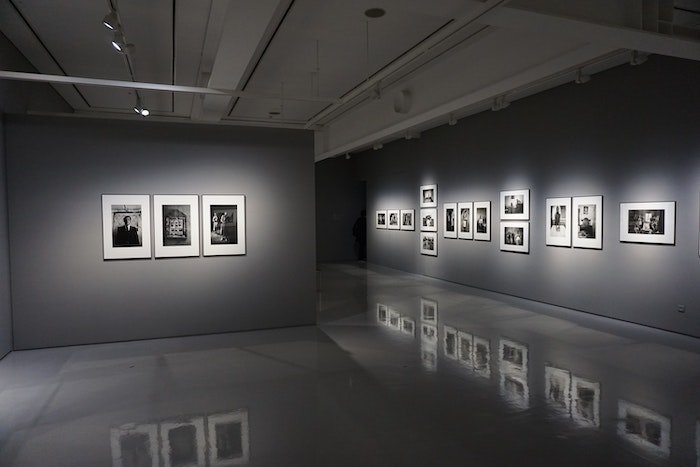 Фотография с фотовыставки. Мягкий свет освещает черно-белые фотографии, выставленные на стене.