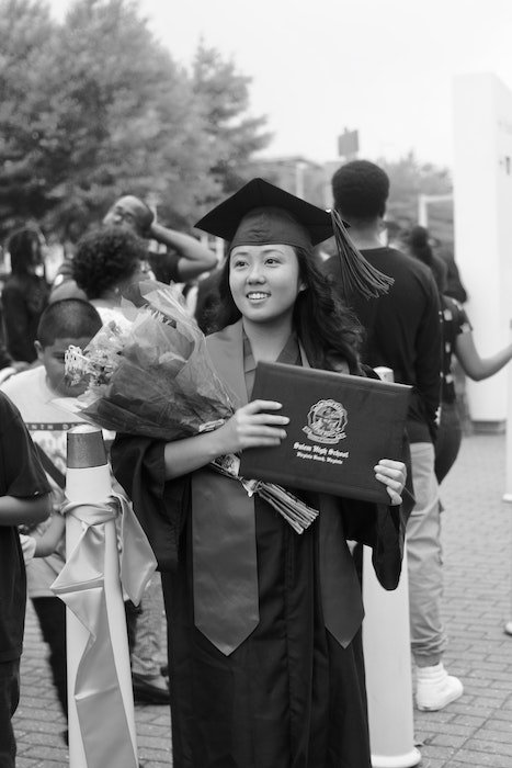 Черно-белая фотография выпускницы школы с цветами и дипломом