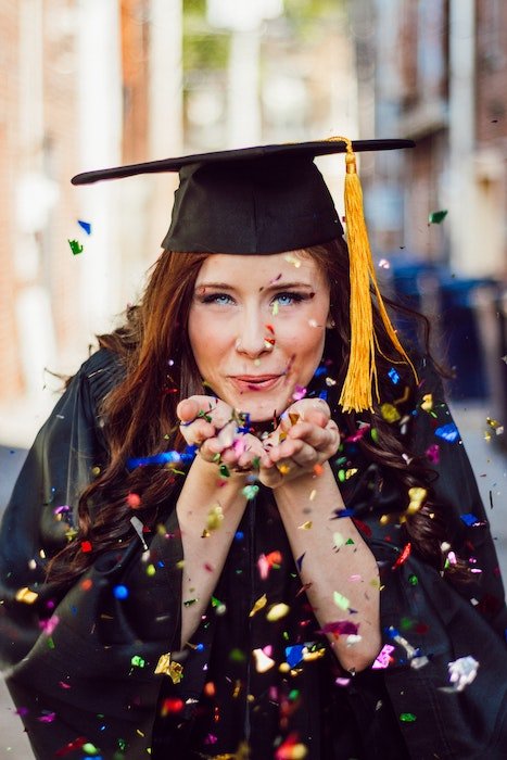 Выпускница средней школы выдувает конфетти из рук как пример уникальной идеи для выпускной фотографии