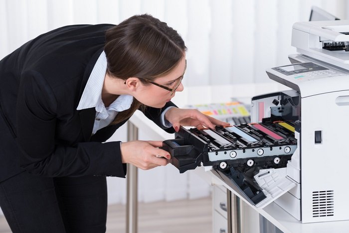 Женщина перезаряжает картриджи в принтере с автоматической подачей документов